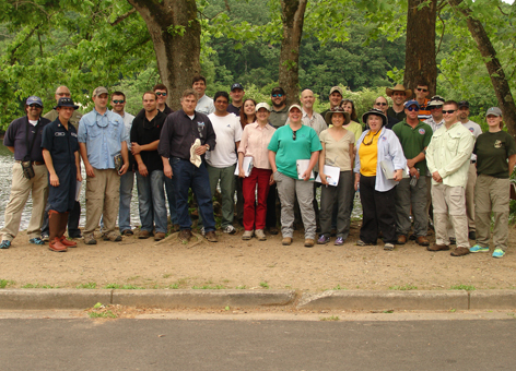 A group of adults standing outside in front of trees.