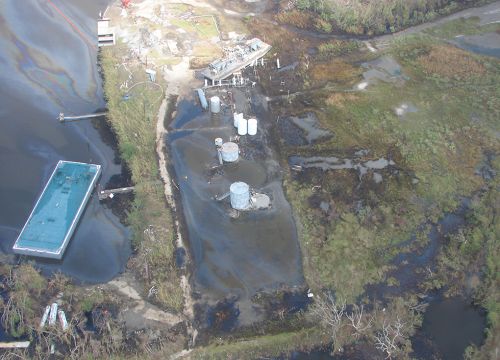 Damaged oil tanks and piping with spilled oil along Gulf Coast.
