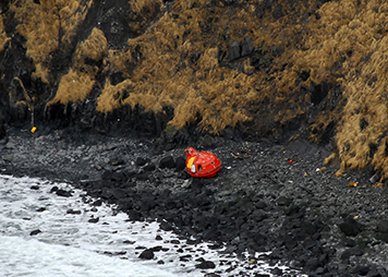 A life raft from grounded rig Kulluk sits on the rocky beach.