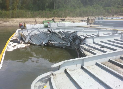 A view of damaged barge with boom and sorbent pads in the water.