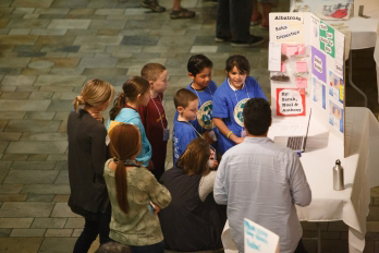 A group of students present on marine debris in front of a stand-up poster.