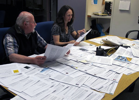 Man and woman with a desk covered in scientific papers.