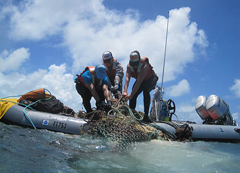 Scientists load onto a small boat marine debris collected at Midway Atoll.
