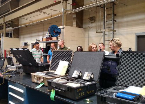 People standing in a lab next to chemical testing equipment.