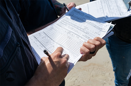 A student shown writing notes on shoreline conditions on a SCAT form as part of participation in NOAA’s SCAT training.