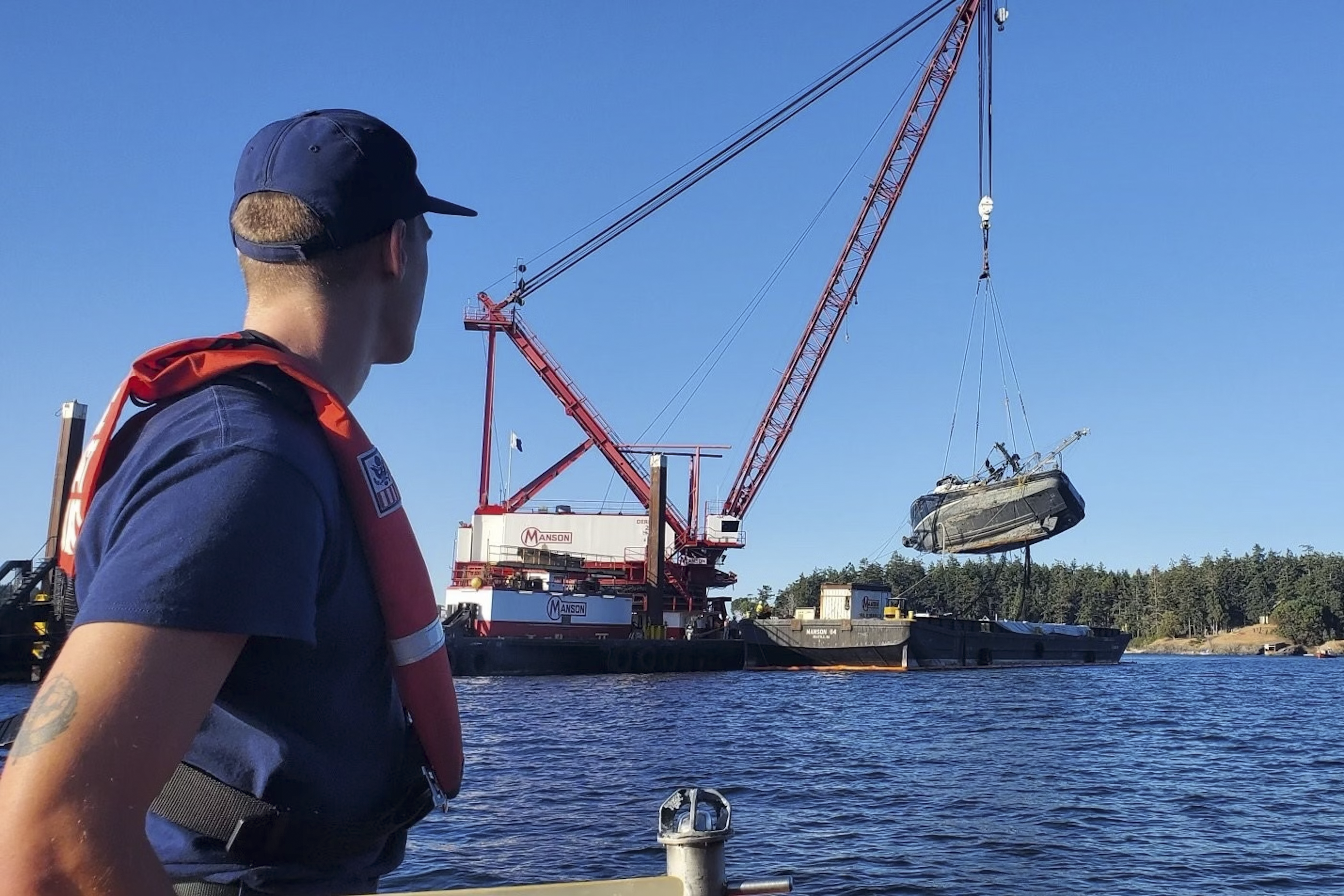 A Coast Guard member watches the F/V Aleutian Isle being lifted onto a barge off San Juan Island on Sept. 21, 2022. Image credit: U.S. Coast Guard