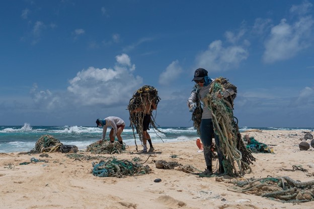 A small team removing ghost nets from the shoreline of Kamole (Laysan island) (Credit: Andrew Sullivan-Haskins, Papahānaumokuākea Marine Debris Project).