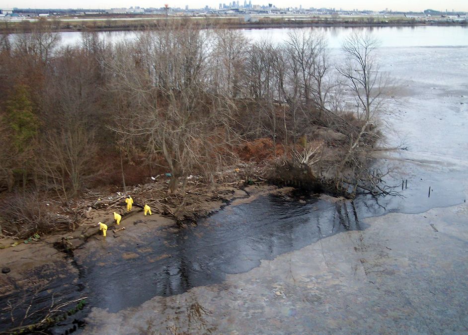 Aerial shot of responders in yellow hazardous materials suit assessing the oiled shoreline of Little Tinicum Island, part of William Penn State Forest, on the Delaware River.