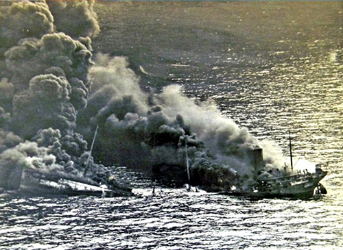 A vessel half submerged in the open ocean with plumes of smoke coming out of it.