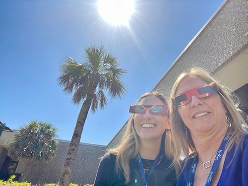 Two NOAA Marine Debris Program staff snap a selfie outside donning eclipse glasses.