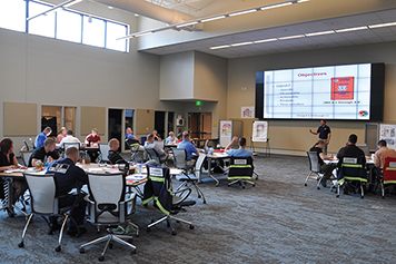 Coast Guard members sitting in a classroom with a presentation on the screen.