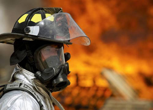 Man in chemical protective mask with fire in background.