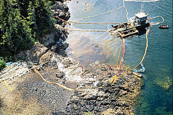 Photo: Aerial shot of maxi-barge and shoreline workers cleaning a beach.
