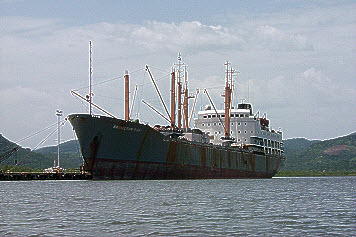 Large rusting vessel in harbour.