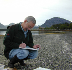 A spill responder on a gravel beach, making hand-written notes.