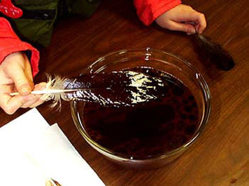 A student dips feather into a bowl of mixed oil and water.