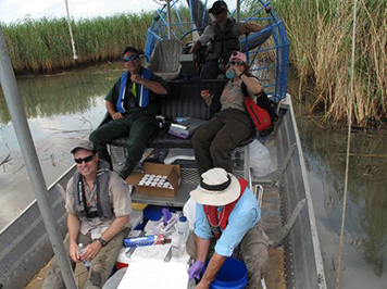 People in a boat in a marsh.