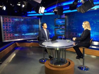 A man and a woman on a newscast set. 