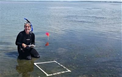 A woman in a wetsuit and snorkeling gear in water. 