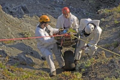 A close-up shot of three people rappel down to a pocket beach.