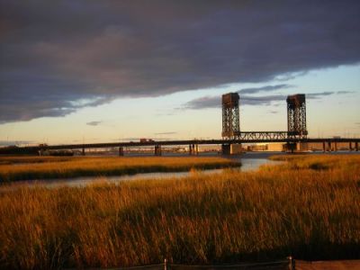 River running through a marsh; bridge in background.