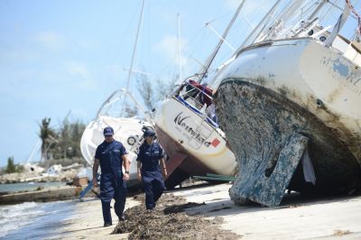 Two people walk by a vessel, tipped on its side on land.