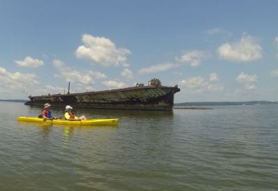 Skeleton of an old vessel in water with a yellow kayak nearby.