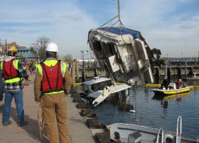 A response team oversees the removal of a sunken boat that was discharging oil.