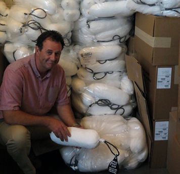 Aaron Barnett holds a bilge sock next to stacks of them.