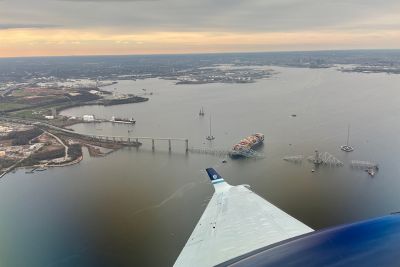 March 28, 2024: View from NOAA King Air N68RF aircraft during a navigation survey following the collapse of the Francis Scott Key Bridge in Baltimore. The bridge and the MV Dali, the container ship involved in the incident, are visible. (Image credit: Lt. Eric Fritzsche/NOAA Corps).