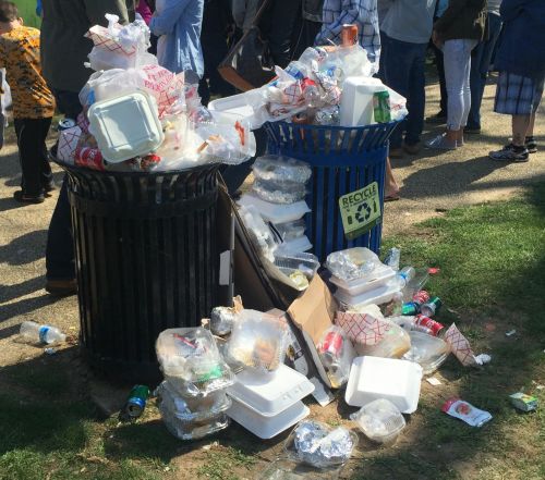 Two garbage cans overflowing.