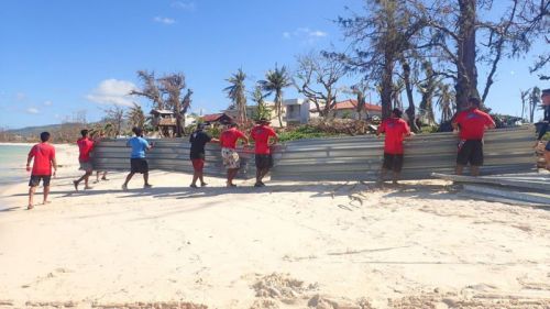 A group of people hauling a large piece of metal.