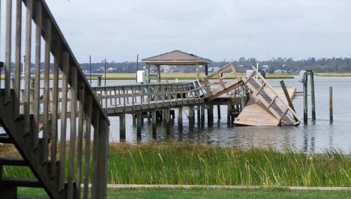 A dock broken and partially lying in the water. 