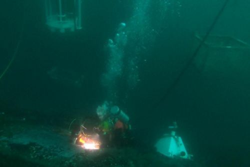 A diver hot tapping into a vessel.