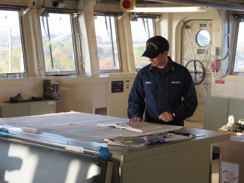 A man on a boat looking at a book and a map.