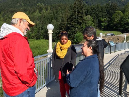 Four people standing together talking. 