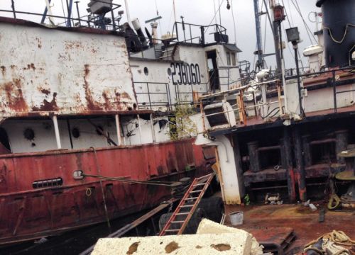 Side view of a rusty, abandoned ship.