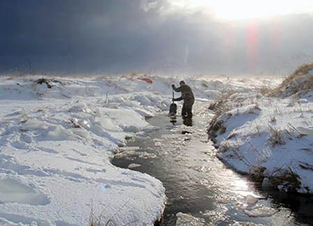 Person working in a stream in a frozen environment.