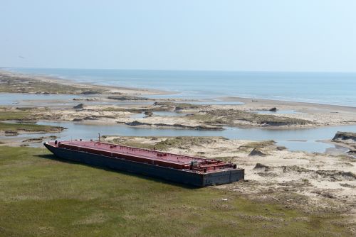 Grounded barge next to body of water.