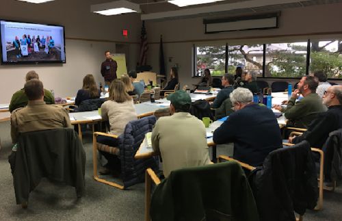 People seated in a classroom with a screen in the front of the room.