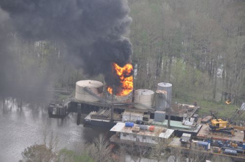 Fire burning on an oil platform on the water.