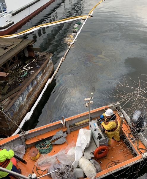 Oil floating on water next to two vessels. 