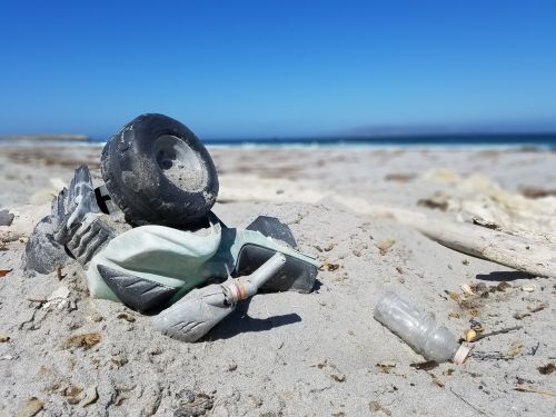 Broken plastic toy and bottle left on the beach.