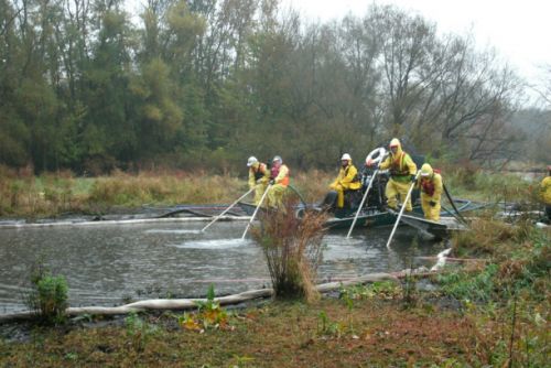 To clean sediment following the oil spill in the Kalamazoo River, Michigan, in July 2010, workers sprayed sediment with water and agitated sediment by hand with a rake. Workers around a body of water.