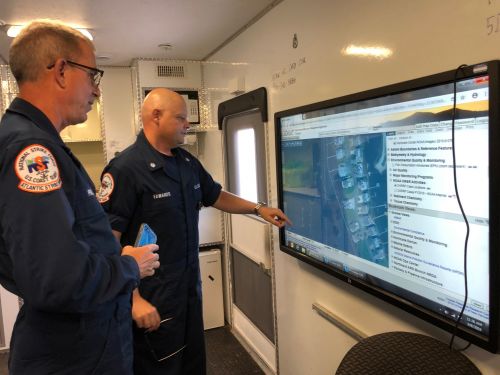 Two people looking at a large screen.