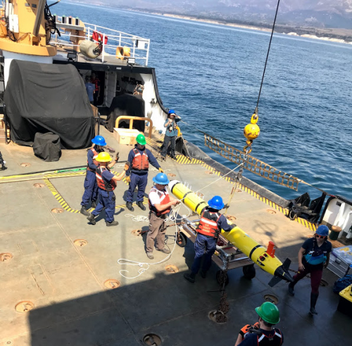 People working with an AUV on the deck of a vessel.