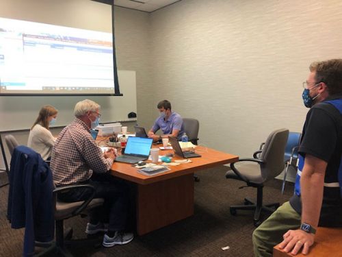 Masked group meeting in a conference room.