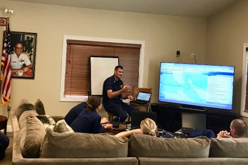 Man lecturing students who are seated on a couch.