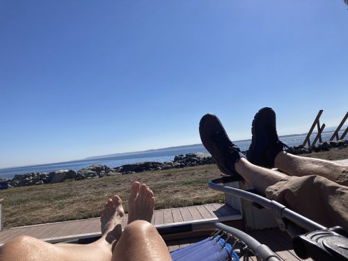 View of shoreline from the perspective of two people on chaise lounges.