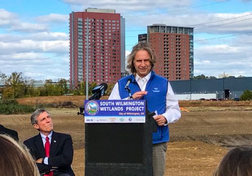 Man speaking at a lectern outdoors.